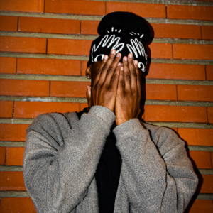 Un homme portant un bonnet les mains sur le visage